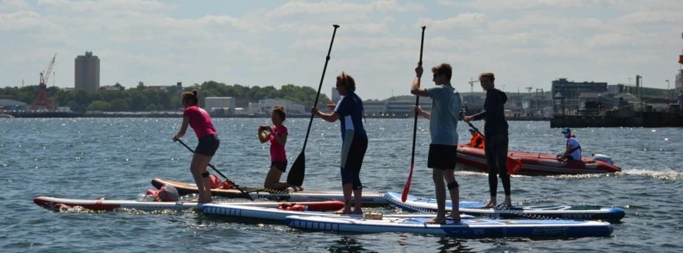 Stand-Up-Paddler auf der Kieler Förde, im Hintergrund ein Schlauchboot
