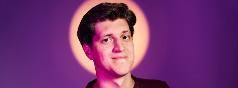 Ein Mann mit dunklen Haaren vor einem violetten Hintergrund