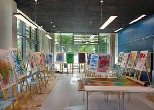 Innenraum einer Schule mit Tischen und Stühlen vor Fenstern mit Sonne im Hintergrund