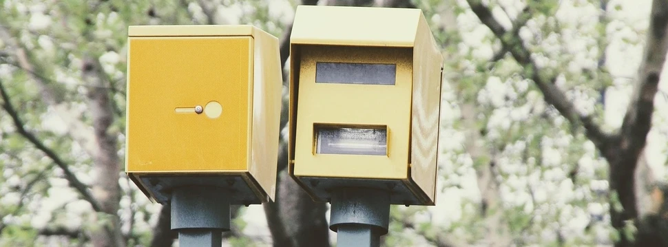 Ein Blitzer an einer Straße mit Bäumen im Hintergrund