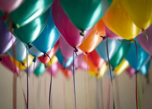 Bunte Luftballons schweben, an ihnen hängt ein Band