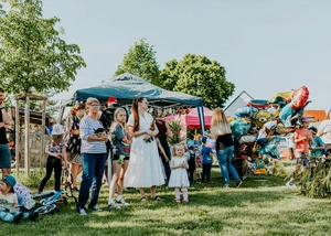 Menschen bei einem Spielplatzfest, bei dem mehrere Pavillons aufgebaut sind und verschiedene Aktivitäten angeboten werden
