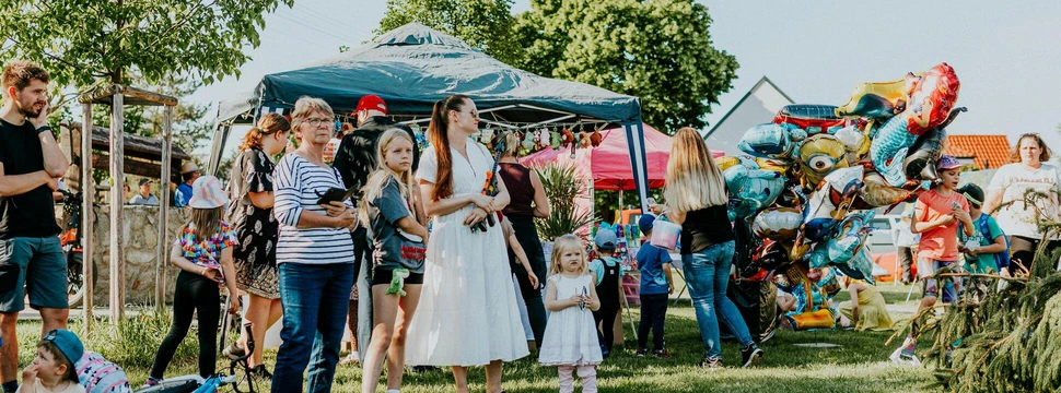 Menschen bei einem Spielplatzfest, bei dem mehrere Pavillons aufgebaut sind und verschiedene Aktivitäten angeboten werden