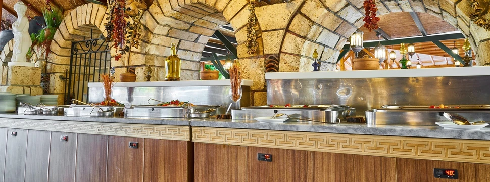 Mehrere Metallbehältnisse mit Essen darin vor Torbögen aus Stein