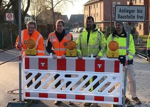 Mehrere Menschen in Warnwesten hinter einer Absperrbarke
