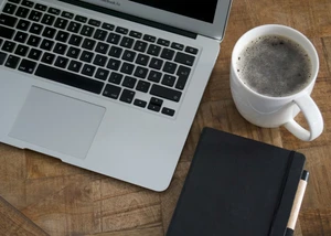Digitales Arbeiten mit Laptop, Kaffeebecher und Notizbuch