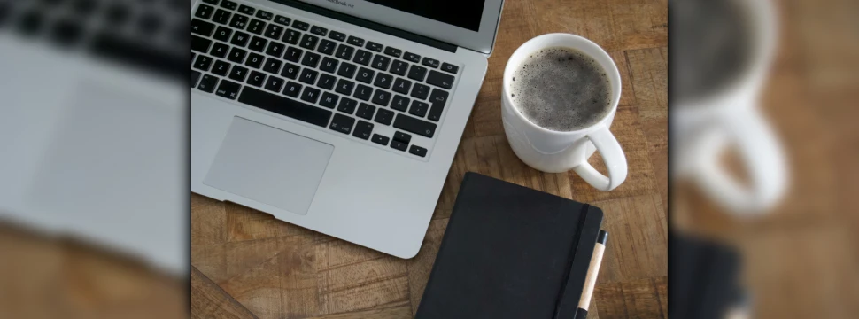 Digitales Arbeiten mit Laptop, Kaffeebecher und Notizbuch