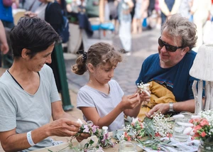 zwei Erwachsene und ein Kind binden einen Blumenkranz