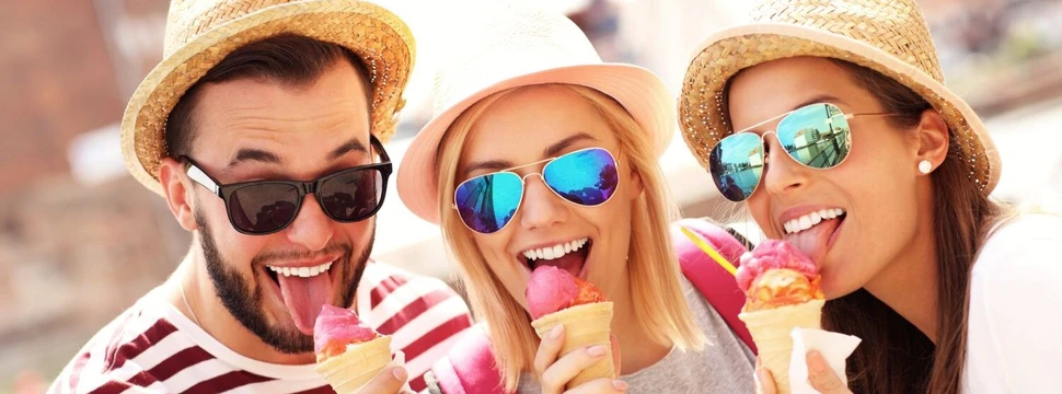 Drei Erwachsene mit Sommerhut, Sonnenbrille und Eiscreme