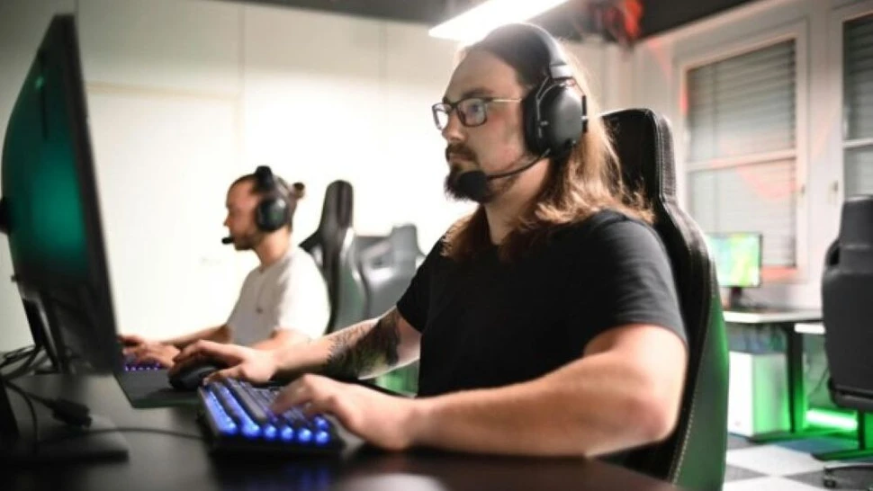 Mann sitzt vor einem Computer und drückt Tasten auf der Tastatur