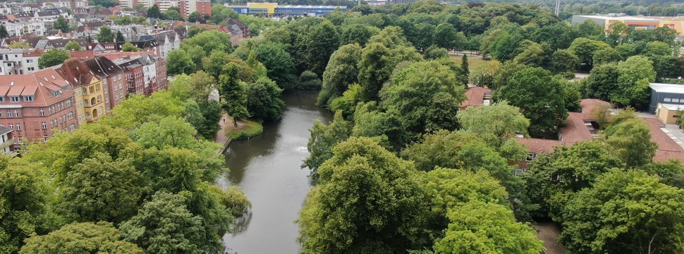 Luftaufnahmen von einem Park. In der Mitte ist ein großer Bach zu sehen