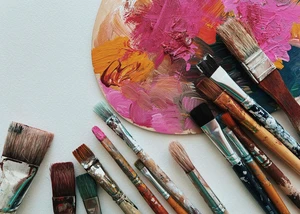 Pinsel und eine Farbpallete liegen benutzt auf einen Tisch