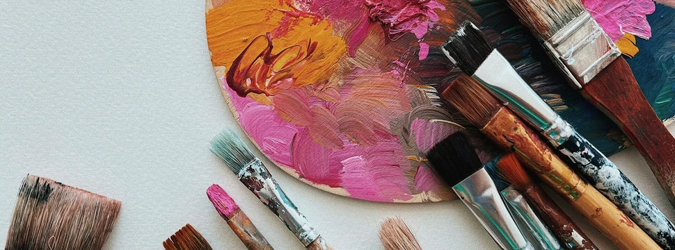 Pinsel und eine Farbpallete liegen benutzt auf einen Tisch