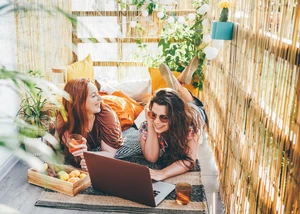 Auch in Kiel prägen zunehmend individuell gestaltete Balkone das Stadtbild. Zwei Frauen mit Laptop liegen auf einem Balkon in der Sonne