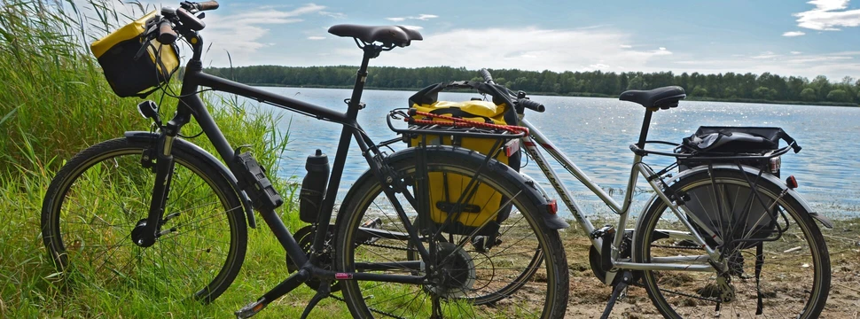 Zwei Fahrräder stehen am See, gesattelt mit Gepäcktaschen
