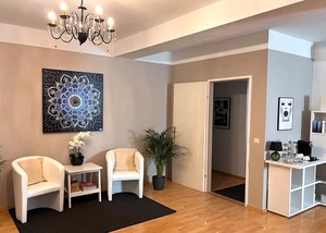 Ein elegant eingerichteter Warteraum mit modernem Design und gemütlicher Atmosphäre Moderner Warteraum mit Kronleuchter, beigen Sesseln, Mandala-Wandbild und Pflanzen in hellen Farbtönen