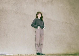 Eine Frau in einem dunklen Oberteil vor einer Wand