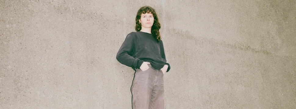 Eine Frau in einem dunklen Oberteil vor einer Wand