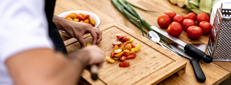 Person schneidet Tomaten auf einen Schneidebrett