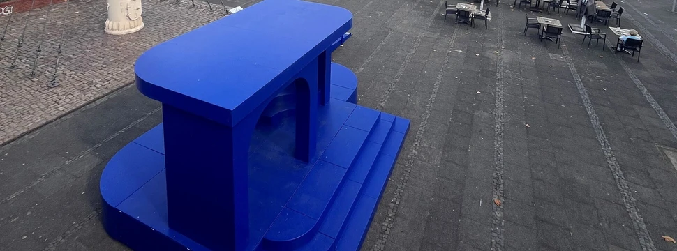 Ein blau gefärbtes Kunstprojekt vor der Kieler Förde mit den Werfttürmen von HDW im Hintergrund