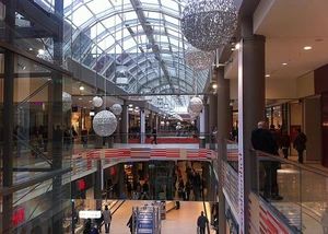 Mit Glasdach überdachter Innenbereich eines Einkaufszentrums mit Rolltreppe