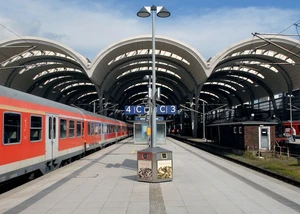 Aussicht auf den Kuppelbau des Kieler Hauptbahnhofs von Bahnsteig 3/4 aus Ein Zug in einem Bahnhof mit Schildern und einem Dach im Hintergrund