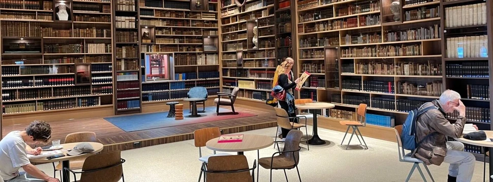 Innenansicht der Landesbibliothek Schleswig-Holstein, bei der mehrere Menschen vor Bücherregalen an Tischen sitzen