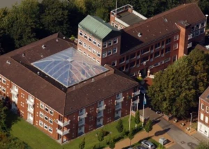 Jugendherberge Kiel mit Glasatrium aus der Vogelperspektive. Luftbild der Jugendherberge Kiel mit Glasüberdachung und rotem Backsteingebäude.