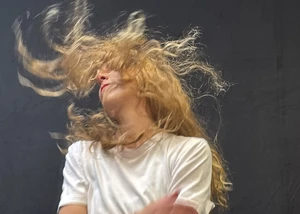 Eine Frau schwenkt ihren Kopf und die Haare fliegen in der Luft