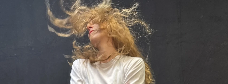 Eine Frau schwenkt ihren Kopf und die Haare fliegen in der Luft