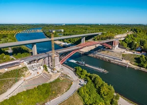 Baustelle der Levensauer Hochbrücke am Nord-Ostsee-Kanal Zwei Brücken vor einem Kanal, an denen derzeit gebaut wird und unter denen gerade ein Schiff langfährt