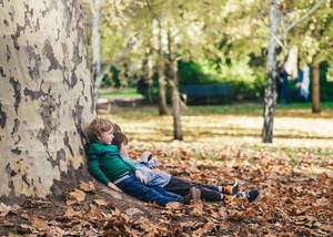 Zwei Kinder sitzen an einem Baum