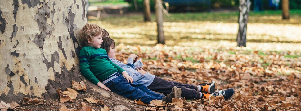 Zwei Kinder sitzen an einem Baum