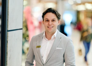 Ein Mann, gekleidet in einem Anzug, mit Menschen im Hintergrund, die unscharf sind