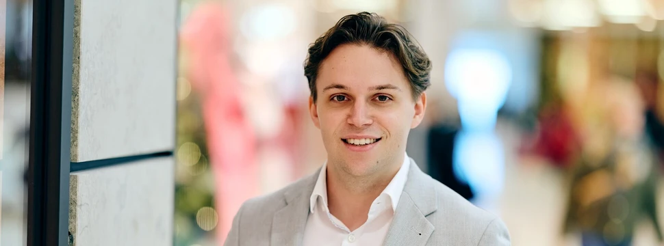 Ein Mann, gekleidet in einem Anzug, mit Menschen im Hintergrund, die unscharf sind