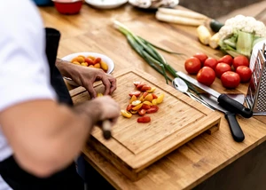 Person schneidet Tomaten auf einen Schneidebrett
