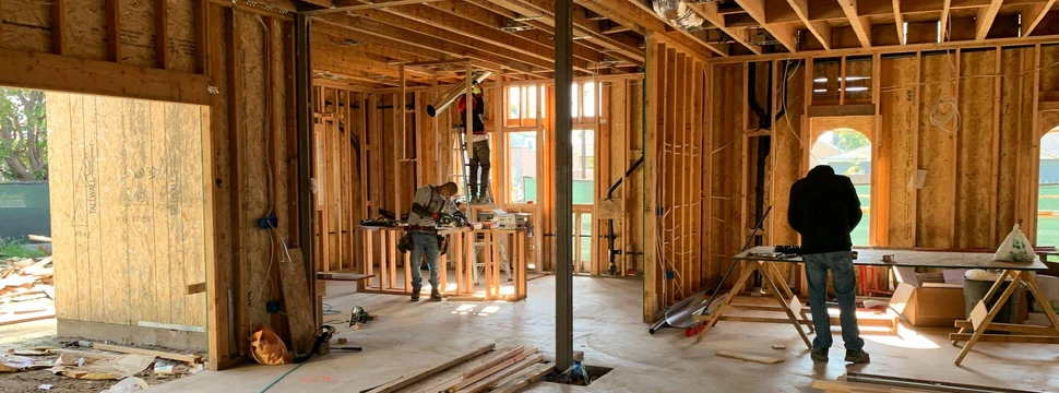 Zwei Menschen auf einer Baustelle, auf der ein Haus gebaut wird