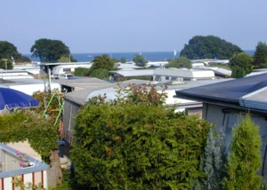 Wohnwagen auf einem Ostsee-Campingplatz mit Blick aufs Meer. Campingplatz an der Ostsee mit Wohnwagen, Meerblick und grünen Hecken bei Sommerwetter.