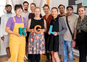 Mehrere Menschen, die zusammen für ein Foto posieren und dabei die Buchstaben K G und L in den Händen halten