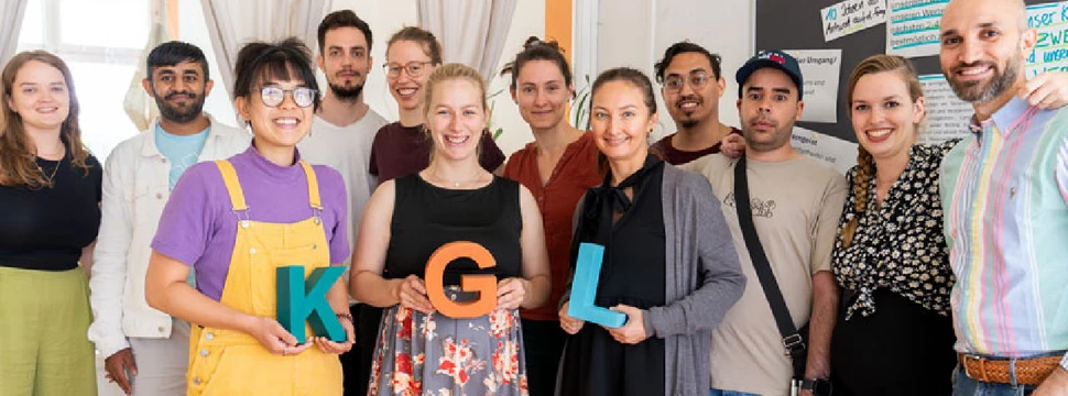 Mehrere Menschen, die zusammen für ein Foto posieren und dabei die Buchstaben K G und L in den Händen halten