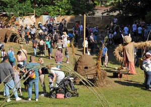 Menschen auf einem Outdoor Festival mit Strohfiguren und Mitmachaktionen auf einer Wiese