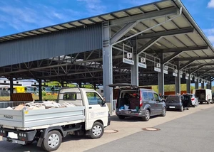 Eine Garage, vor der mehrere Autos stehen und dort Wertstoffabfälle abgeben können