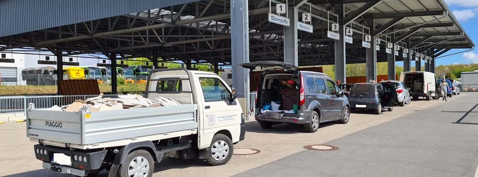 Eine Garage, vor der mehrere Autos stehen und dort Wertstoffabfälle abgeben können