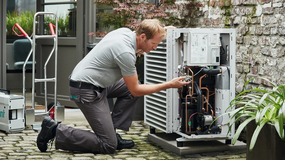 Ein Mann in einem grauen Oberteil vor einer Wärmepumpe