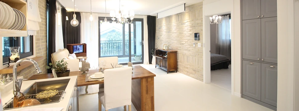 Die Inneneinrichtung einer Ferienwohnung mit Stühlen, einer Küche und Tischen und einem Balkon im Hintergrund