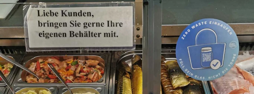 Ein blauer Aufkleber eines Kieler Vereins, der an der Scheibe eines Fischhändlers angebracht ist und auf eine Kampagne zur Müllvermeidung hinweist