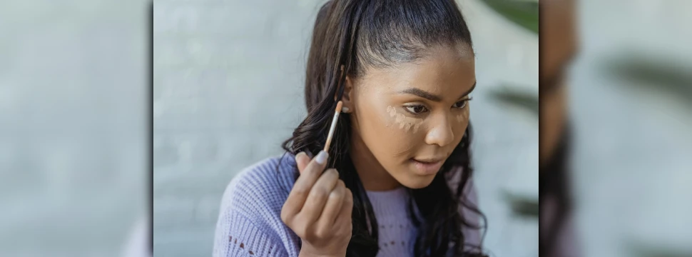 Eine junge Frau, die sich Concealer aufträgt