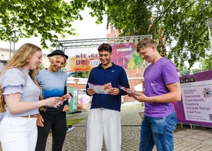Mehrere Menschen vor dem Stand der Kieler Uni an der Kiellinie, die sich gerade Flyer anschauen