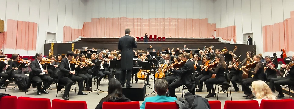 Mehrere Menschen in einem großen Raum mit roten Sitzen und Instrumenten in der Hand