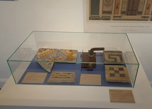 Alte Kacheln und Deckenverzierungen in einer Vitrine in einem Museum